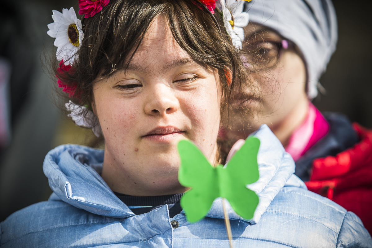 dziewczyna z Zespołem Downa trzymająca papierowego, zielonego motyla