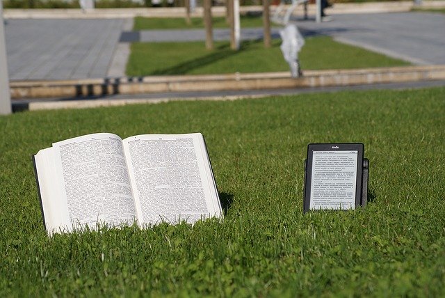 E-book lezy na trawie obok książki